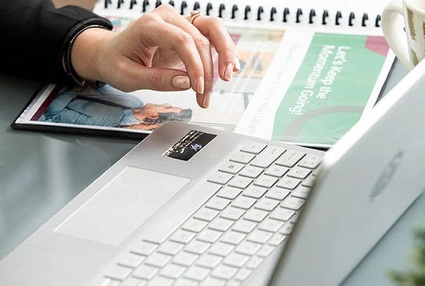 a spiral-bound notebook beside an open laptop