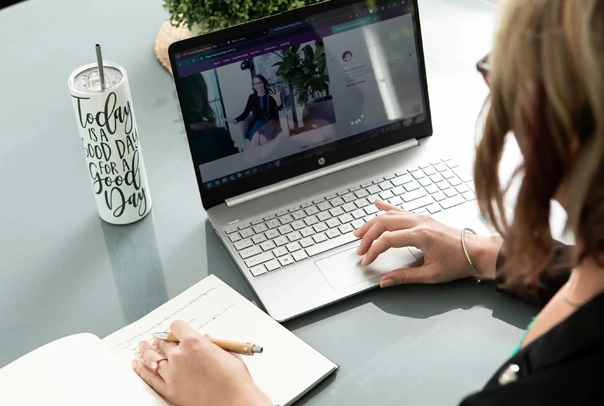 a spiral-bound notebook beside an open laptop